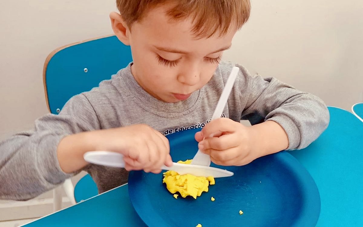 Criança treinando o uso de garfo e faca